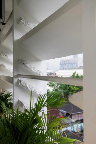 a room with white walls and a window with plants at C'HOUSE Bangkok in Pom Prap