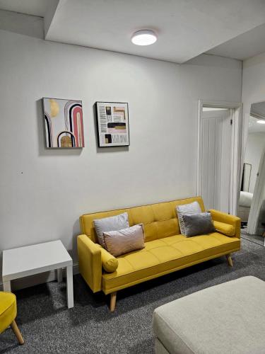 a living room with a yellow couch and a table at Spacious room with private living room in Bristol