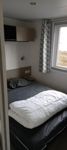 a bedroom with a bed and a window with a cat on it at MH 215 Bois Dormant 6 personnes in Saint-Jean-de-Monts