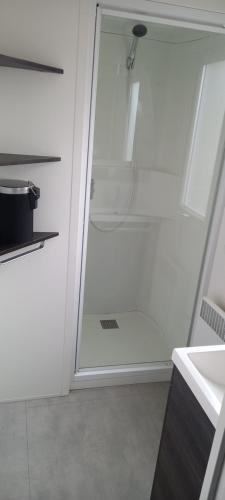 a glass shower door in a white bathroom at MH 215 Bois Dormant 6 personnes in Saint-Jean-de-Monts