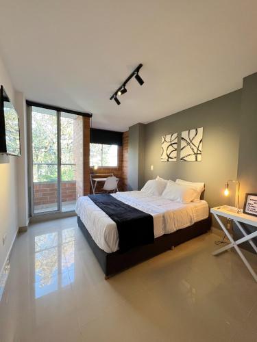 a large bedroom with a large bed and a table at LOFT SOHO ICÓNICO CON BALCÓN in Sabaneta