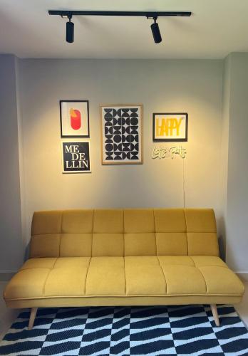 a yellow couch in a room with pictures on the wall at LOFT SOHO ICÓNICO CON BALCÓN in Sabaneta