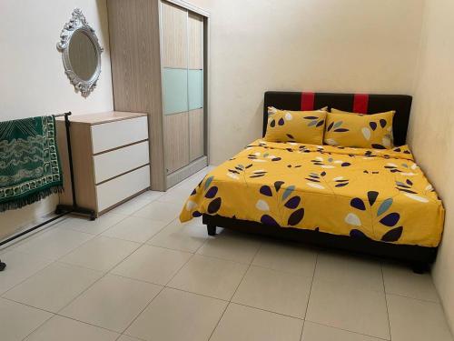 a bedroom with a bed with a yellow comforter at Homestay Samsul Sungkai in Sungkai