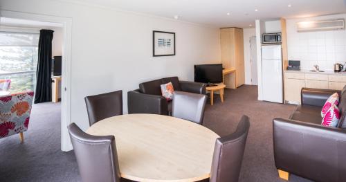 a room with a table and chairs and a kitchen at Scenic Hotel Te Pania in Napier