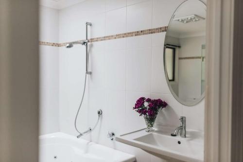 Baño blanco con lavabo y espejo en Coromandel Lodge, Berrima, en Berrima