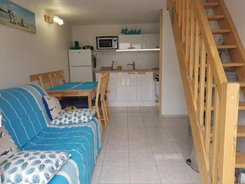 un salon avec un canapé bleu et une cuisine dans l'établissement Maisonnette 4 pers. près plage, piscine et parking - FR-1-194-260, à La Tranche-sur-Mer