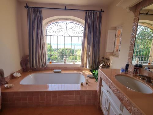 une grande salle de bains avec une grande baignoire et une fenêtre. dans l'établissement Villa 6 pièces climatisée avec piscine privée à Grimaud - FR-1-780-10, à Grimaud