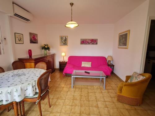 un salon avec un lit rose et une table dans l'établissement Appartement T2 calme avec parking, balcon, proche centre-ville et plage à Sainte-Maxime - FR-1-780-22, à Sainte-Maxime