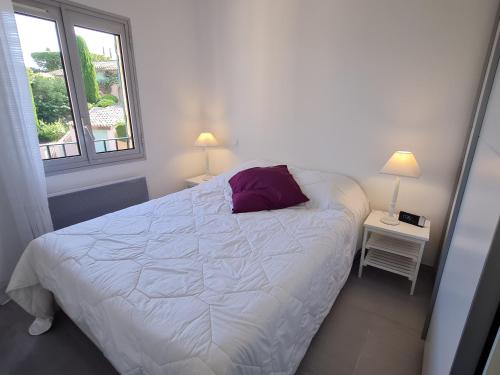- une chambre avec un lit doté d'un oreiller violet et d'une fenêtre dans l'établissement Appartement 3 pièces, clim, piscine, parking à Sainte-Maxime - FR-1-780-24, à Sainte-Maxime