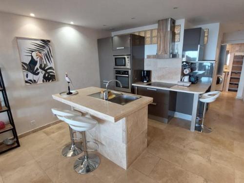 - une cuisine avec un évier et deux tabourets de bar dans l'établissement Appartement climatisé avec piscine, terrasse vue mer et parking à Sainte-Maxime - FR-1-780-38, à Sainte-Maxime