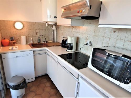 eine Küche mit weißen Schränken und einer Mikrowelle in der Unterkunft Appartement Sainte-Maxime, 1 pièce, 2 personnes - FR-1-780-37 in Sainte-Maxime