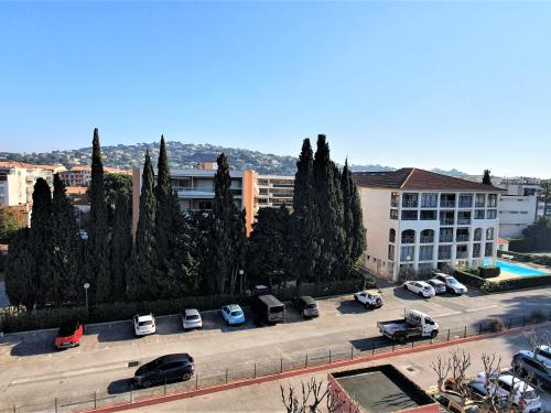 un parking avec des voitures garées et un bâtiment dans l'établissement Studio Centre Sainte-Maxime avec Parking – 2 Pers, Proche Mer, Loggia Équipée - FR-1-780-37, à Sainte-Maxime