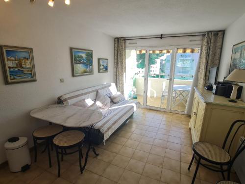 un salon avec un canapé, une table et des chaises dans l'établissement Appartement 2P avec balcon, piscine et parking proche centre de Sainte-Maxime - FR-1-780-40, à Sainte-Maxime