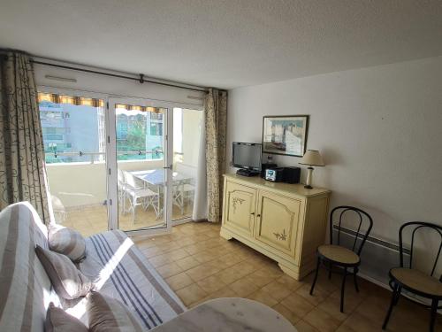 un salon avec un canapé et une télévision et un balcon dans l'établissement Appartement 2P avec balcon, piscine et parking proche centre de Sainte-Maxime - FR-1-780-40, à Sainte-Maxime
