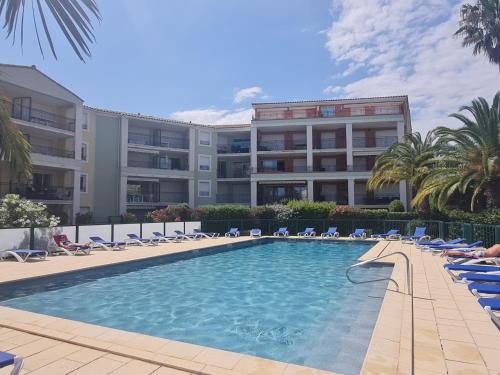 une piscine en face d'un grand bâtiment dans l'établissement Appartement T3 climatisé en rez-de-jardin, piscine, plage et centre-ville à pied - 6 pers, Ste Maxime - FR-1-780-42, à Sainte-Maxime