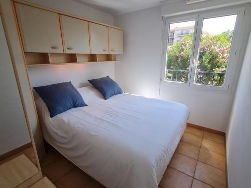 une chambre avec un lit blanc avec des oreillers bleus dans l'établissement Appartement T3 climatisé en rez-de-jardin, piscine, plage et centre-ville à pied - 6 pers, Ste Maxime - FR-1-780-42, à Sainte-Maxime
