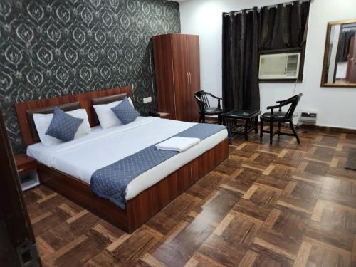 Hotel New City Lite في نيودلهي: غرفة نوم بسرير وطاولة وكراسي