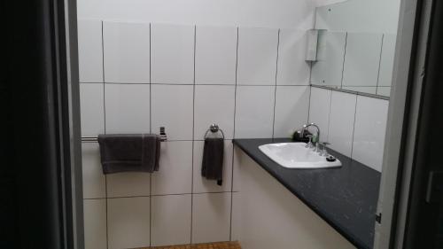 a white tiled bathroom with a sink and a mirror at San Remo Hotel Motel in San Remo