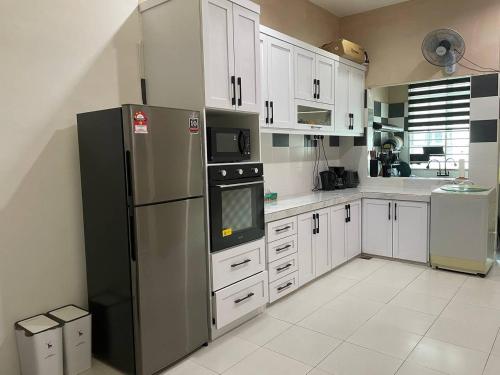 a kitchen with white cabinets and a black refrigerator at Homestay Samsul Sungkai in Sungkai