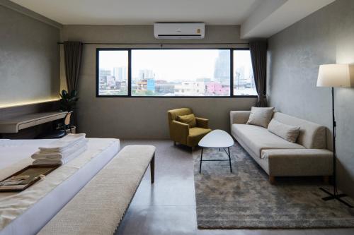 a living room with a bed and a couch at C'HOUSE Bangkok in Pom Prap