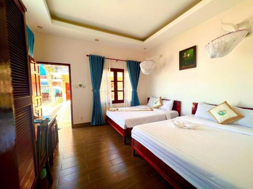 2 Betten in einem Zimmer mit blauen Vorhängen in der Unterkunft Sóng Biển Xanh Mũi Né Resort - by Bay Luxury in Ấp Long Sơn