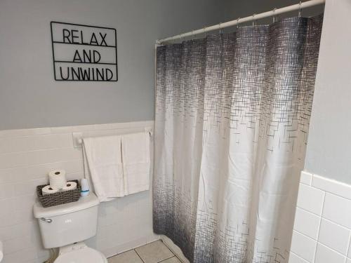 La salle de bains est pourvue d'un rideau de douche et de toilettes. dans l'établissement Willow Way: Cozy Retreat, à Fort Smith