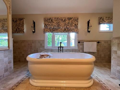 a large bath tub in a bathroom with windows at Collins Cottage - Luxury Accommodation in Bright
