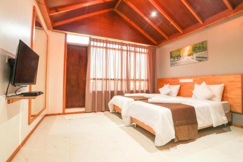 a bedroom with two beds and a flat screen tv at Gaafaru B&B in Gaafaru