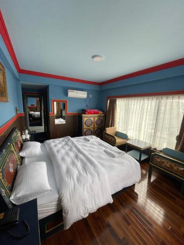 a bedroom with a large white bed and blue walls at Hotel De Purang in Muktināth