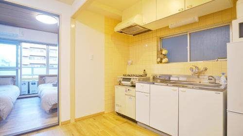 eine Küche mit einem Waschbecken und ein Bett in einem Zimmer in der Unterkunft CowCow Hotel Shinjuku in Tokio