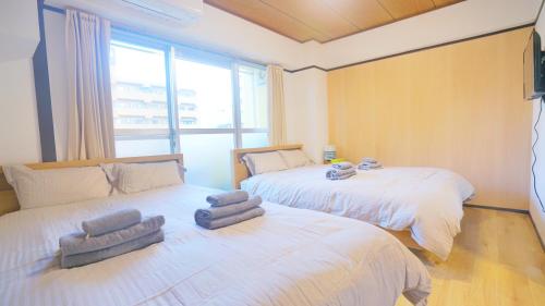 a bedroom with two beds and a large window at CowCow Hotel Shinjuku in Tokyo