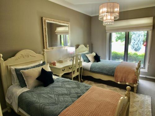 a bedroom with two beds and a desk and a mirror at Collins Retreat - 4 Bedroom home with Pool in Bright