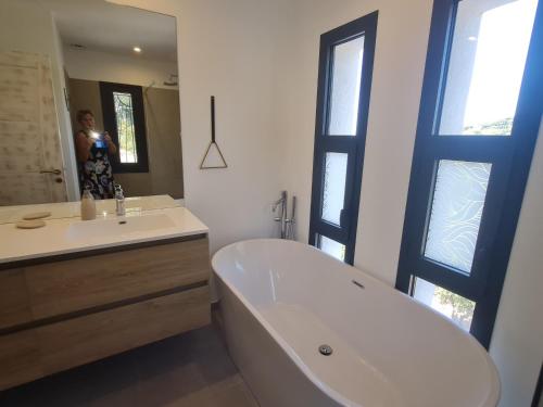 une femme prenant une photo d'une salle de bains avec baignoire et lavabo dans l'établissement Villa climatisée 6 pièces avec piscine privée, 5 chambres, Domaine de La Nartelle - FR-1-780-67, à Sainte-Maxime