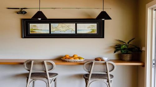 une cuisine avec un comptoir avec deux chaises et une fenêtre dans l'établissement The Little Boatshed, à Hardys Bay