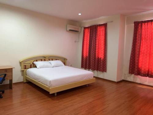 a bedroom with a bed and two windows with red curtains at 1717 Bintulu Homestay 1 in Bintulu