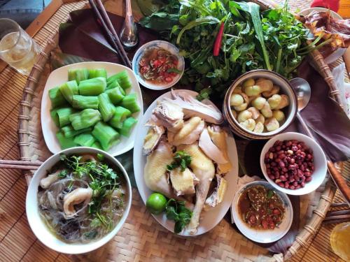a table with plates of food and bowls of vegetables at Kha Bản Homestay in Cao Bằng