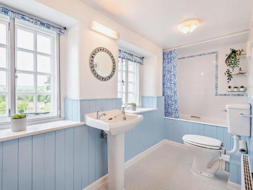 a blue and white bathroom with a toilet and a sink at 4 Bed in Church Knowle DC125 in Corfe Castle