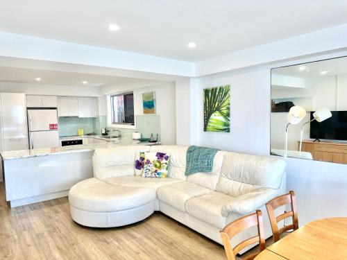 a living room with a white couch and a kitchen at Hillhaven Holiday Apartments in Gold Coast