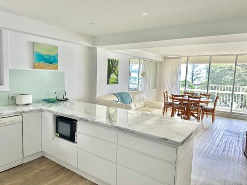 黄金海岸希拉纹假日公寓的一间厨房,配有白色橱柜和一间餐厅