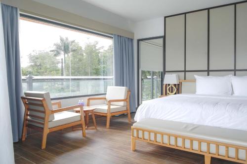 a bedroom with a bed and chairs and a large window at Eroska Villa in Thôn Cát Lợi