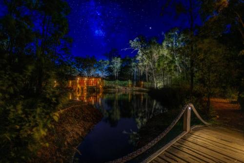 a night view of a pond with a wooden bridge at Nannup Bush Retreat in Nannup