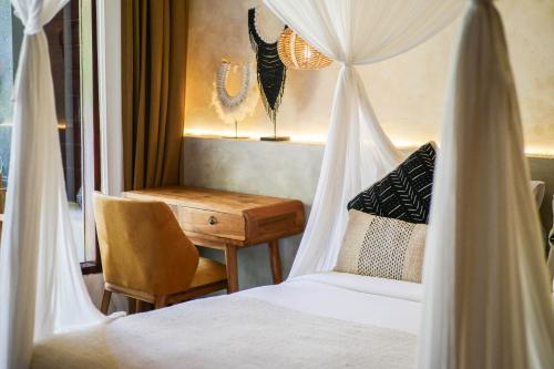 a bedroom with a canopy bed and a desk at Village Bali in Uluwatu