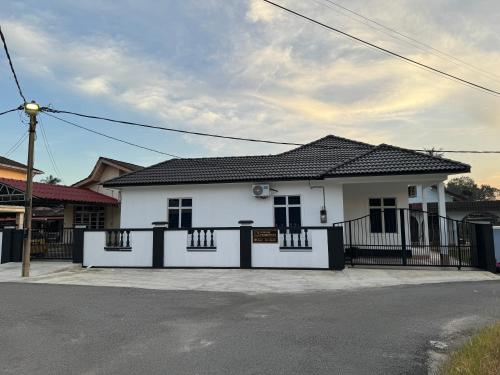 een wit huis met een zwart hek ervoor bij 13 Avenue Homestay in Kota Bharu