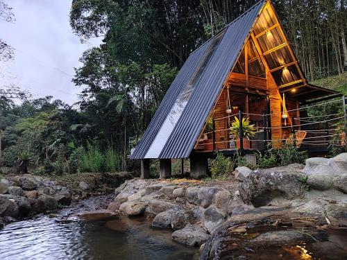 a wooden house with a roof on a river at Senz Glamping - Mindo in Mindo