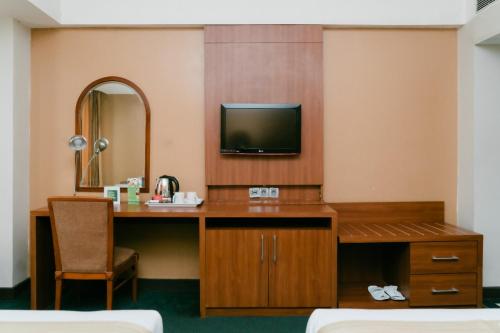 een hotelkamer met een bureau en een televisie bij Horison Ultima Bandung in Bandung