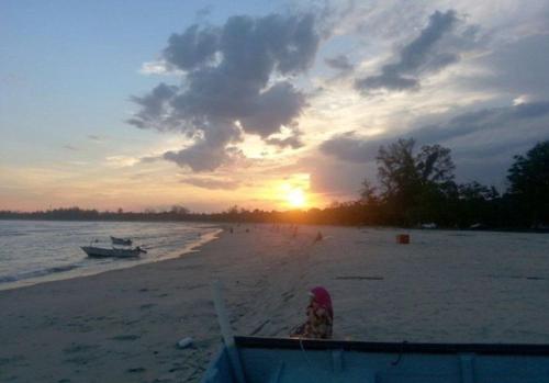 een zonsondergang op een strand met een boot in het water bij A YIE HOMESTAY in Kuantan
