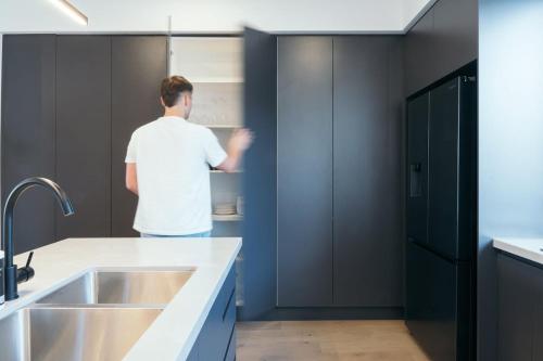 a man in a kitchen looking into a refrigerator at Lusso - Rooftop Views 3BR 3BTH 4 Level Townhouse in Adelaide