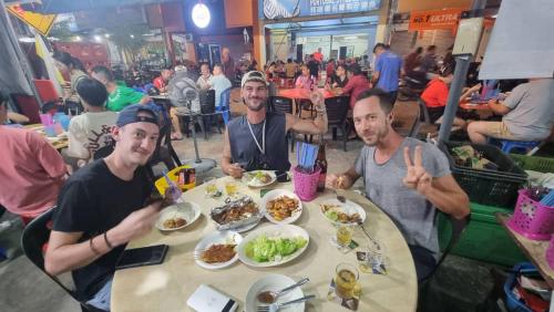 a group of men sitting at a table eating food at ShopLot Hostel Pangkor in Pasir Bogak