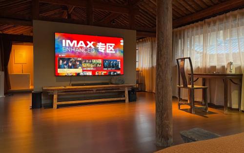 a living room with a large television on a wall at Qushe Snowy Mountain View Art B&B in Lijiang