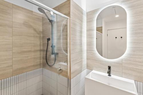 a bathroom with a shower and a sink and a mirror at Elegant Collingwood Apartment with City Views in Melbourne